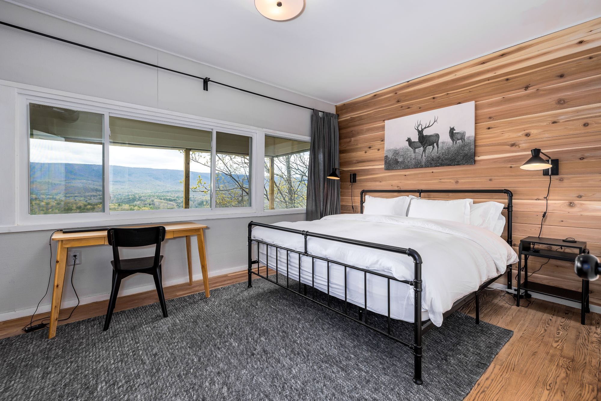 King bedroom with a cedar accent wall and wraparound windows over the valley