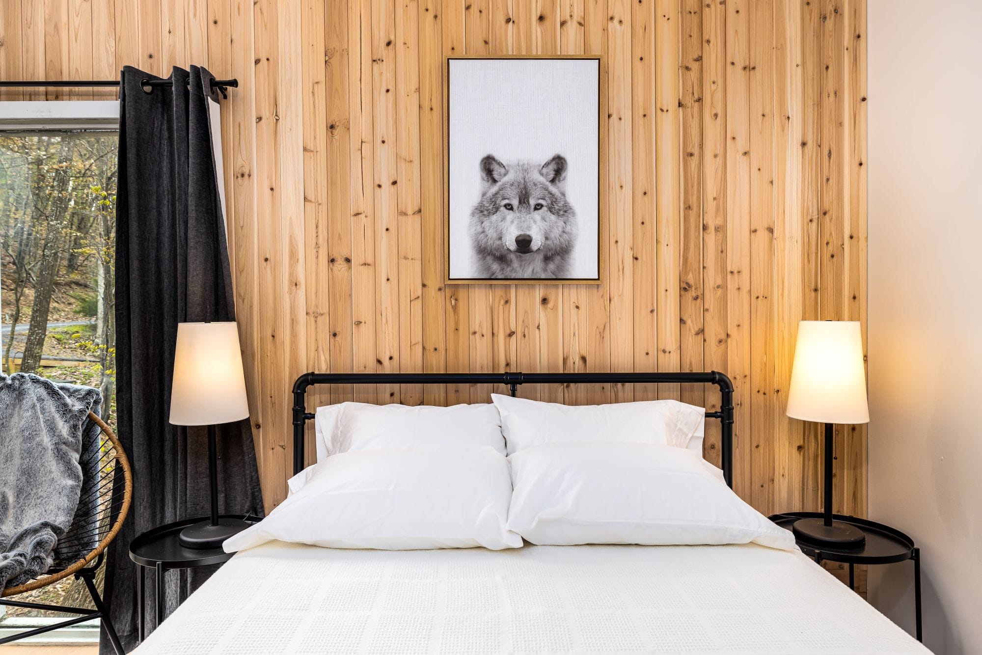 Bedroom with a cedar feature wall, framed wolf print, and matching lamps