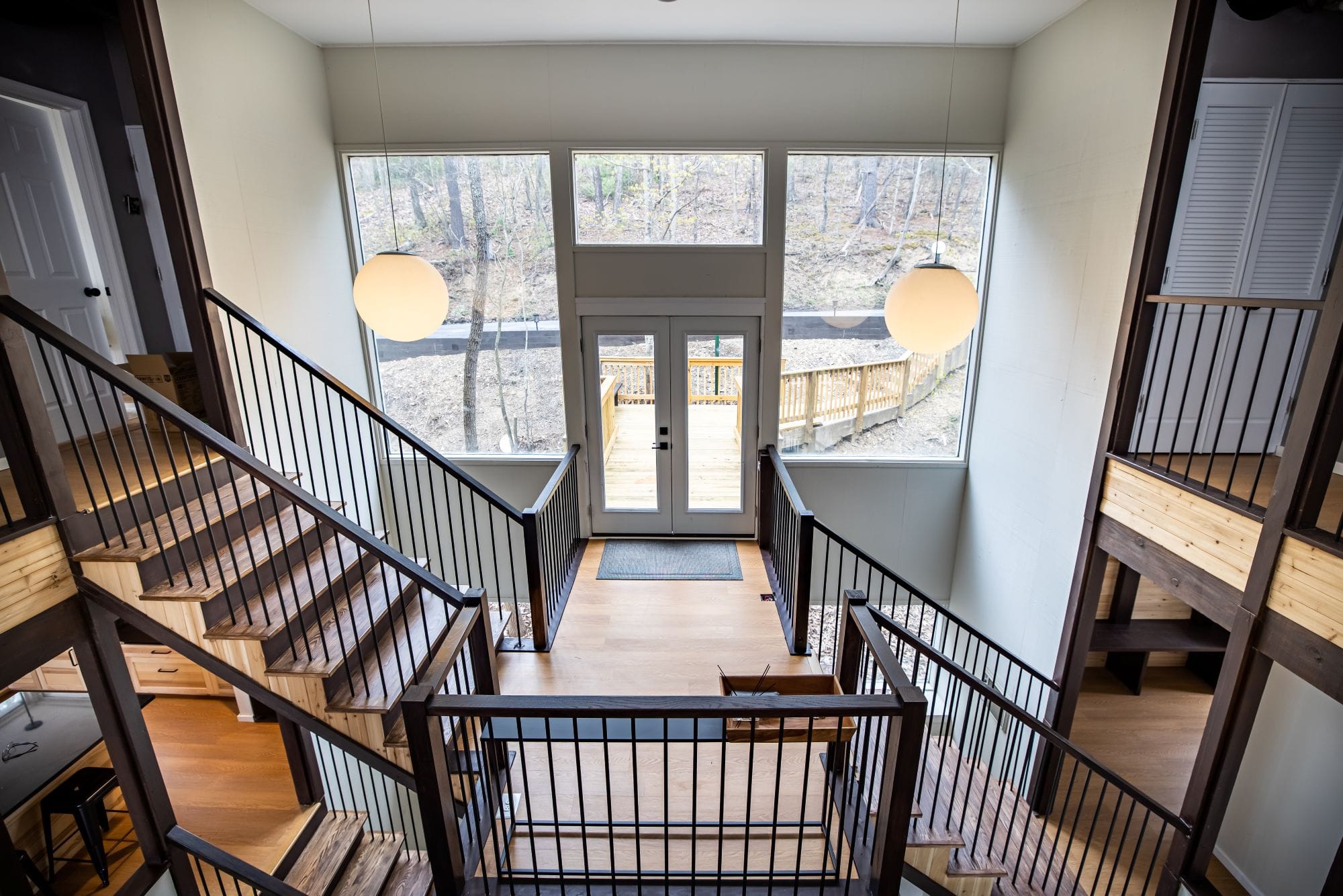 Two-story entry foyer with globe pendants and a wall of glass to the deck