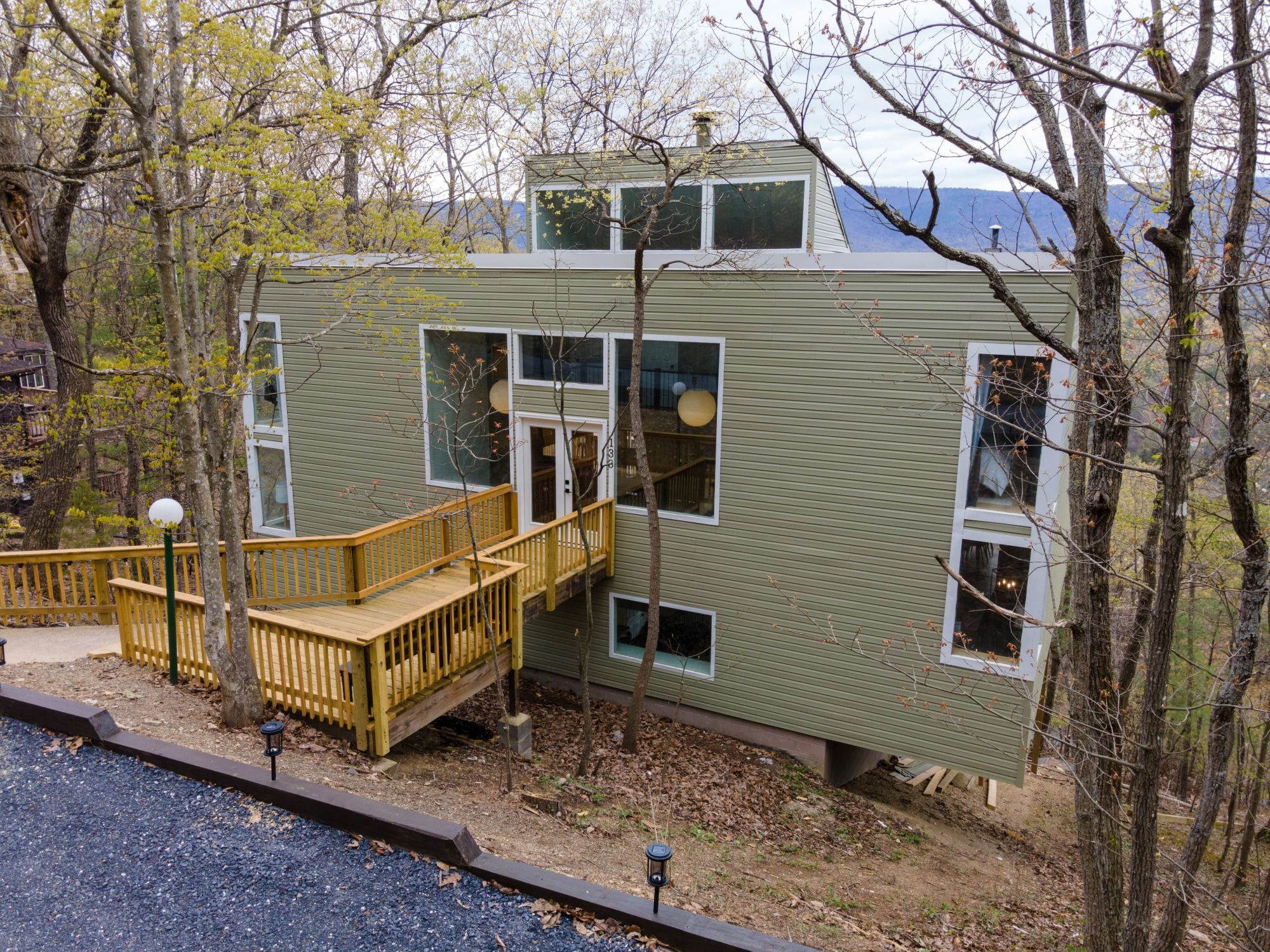 The Chalet's green-sided facade among the trees, with a wraparound deck and ramp