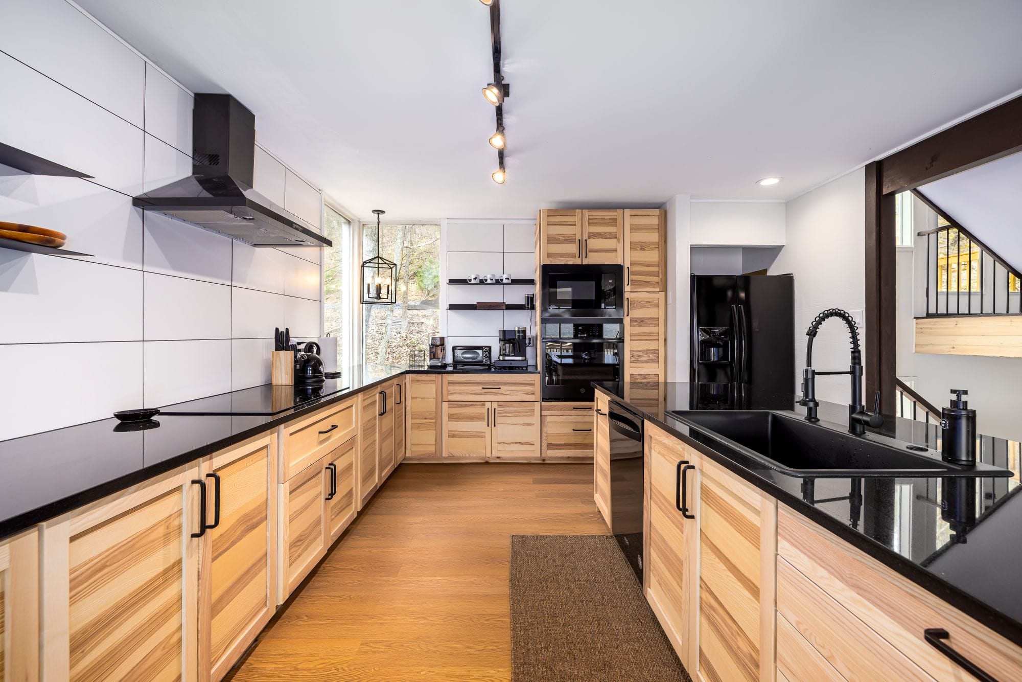 Chef's kitchen with ash cabinets, black quartz counters, and full-size black appliances