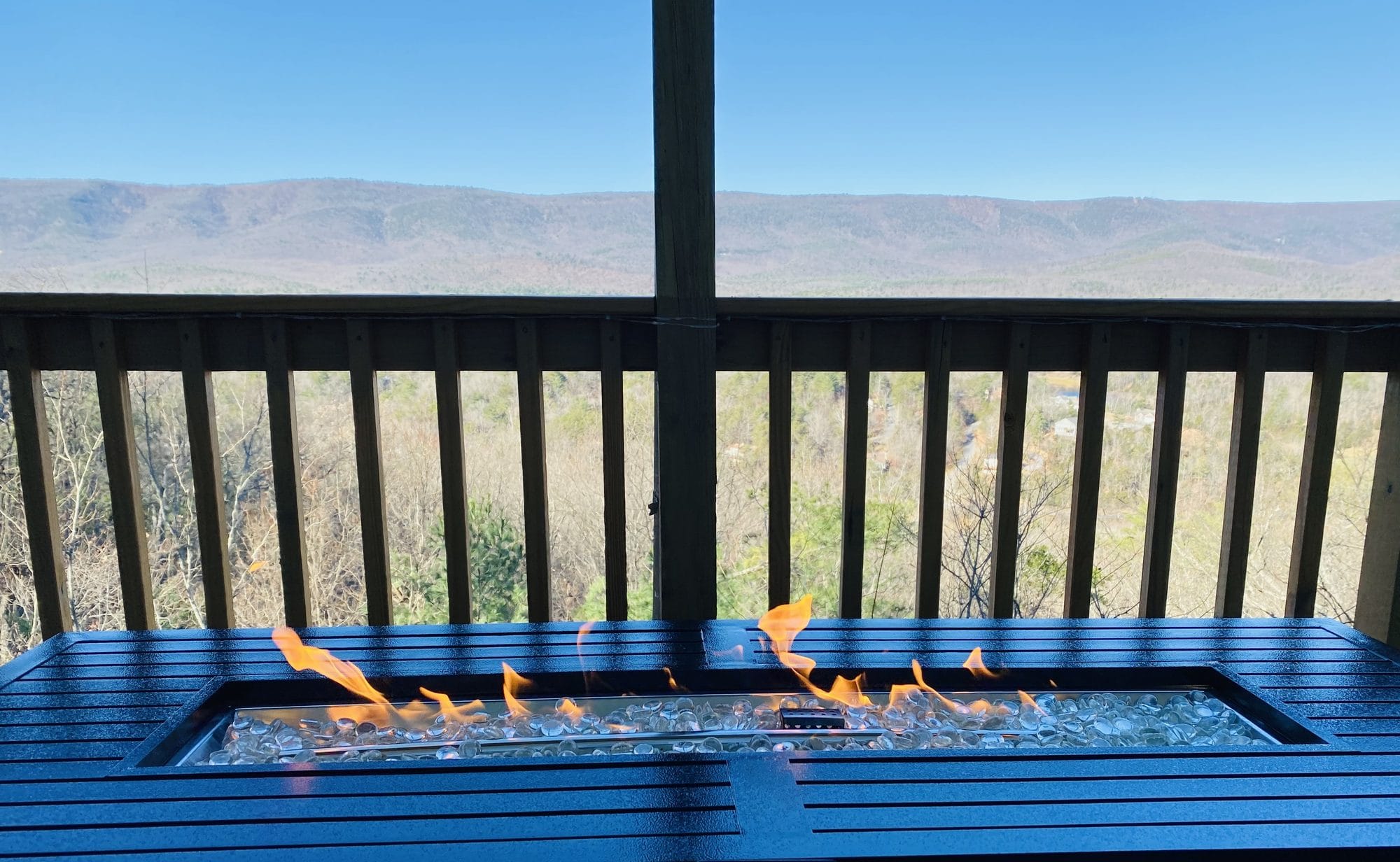 Lit fire table on the covered deck with the mountain ridgeline beyond