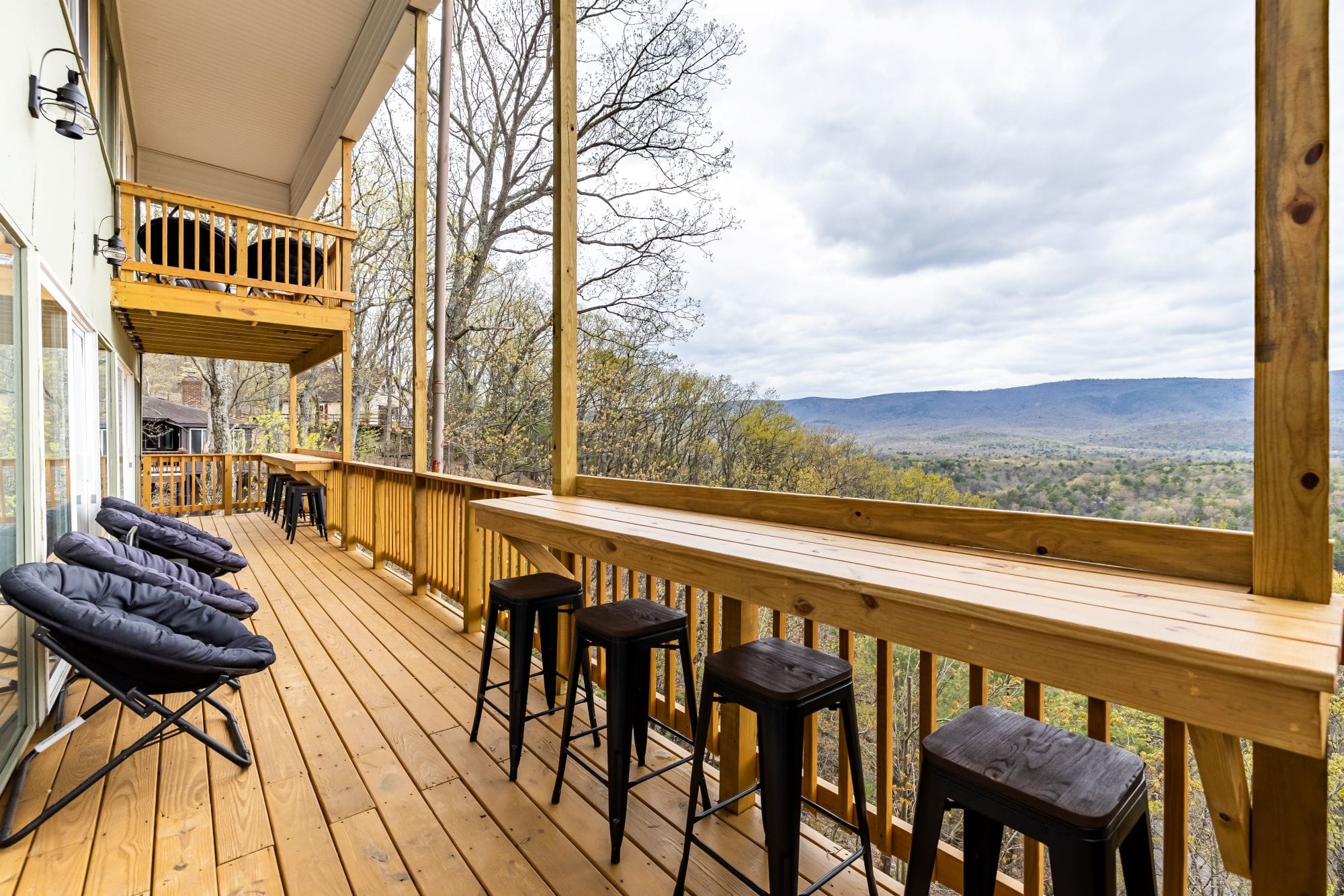 Covered deck with a bar-height counter, stools, and Papasan chairs over the valley