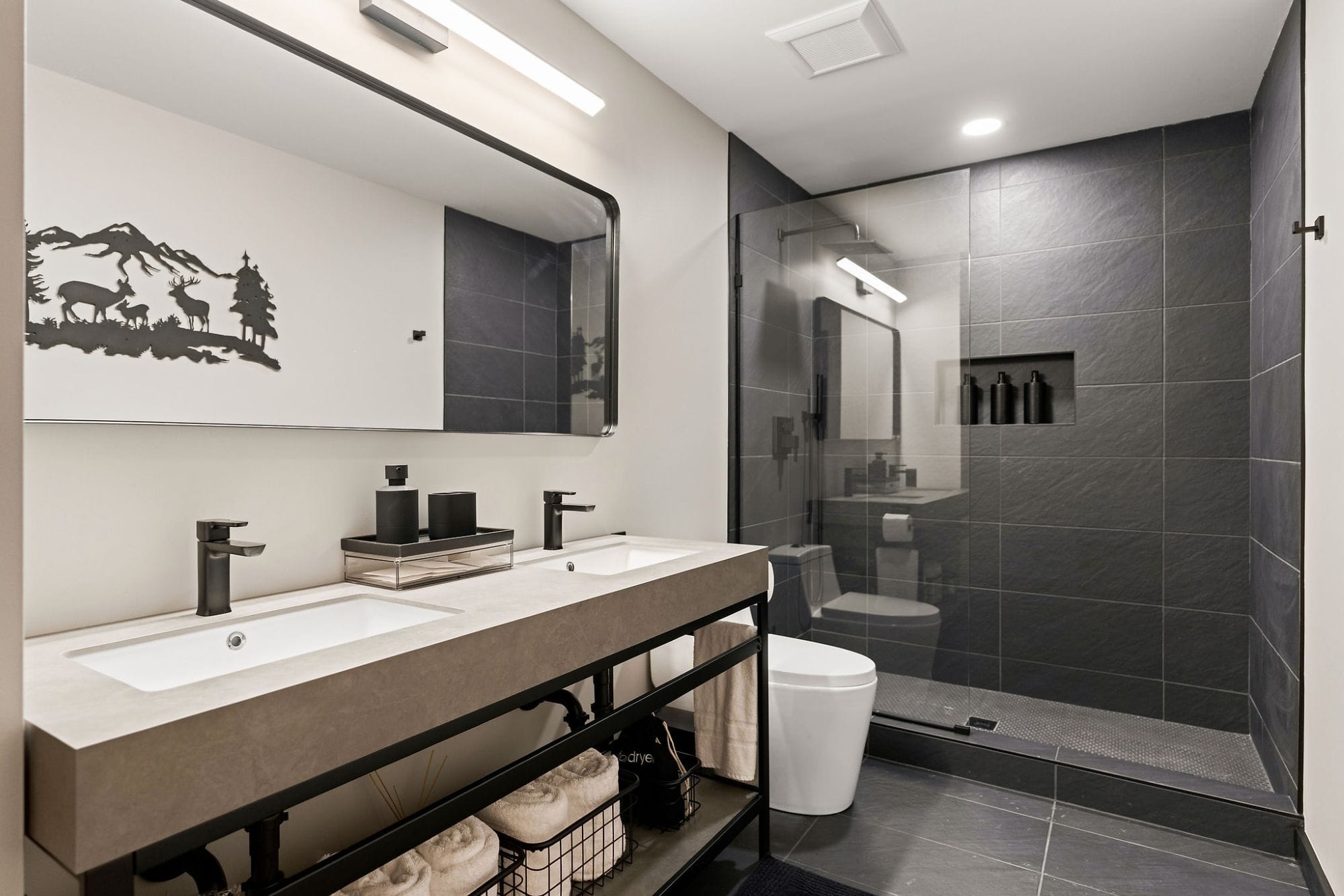 Bathroom with a double vanity, walk-in shower, and mountain metal art
