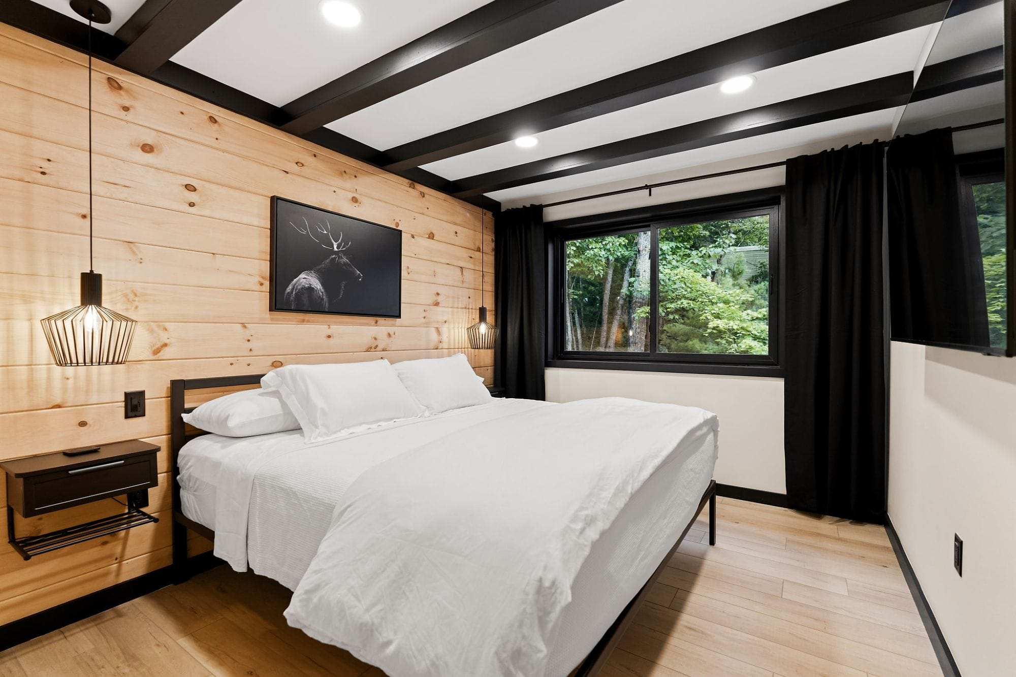 Bedroom with a cedar accent wall, elk print, and black ceiling beams