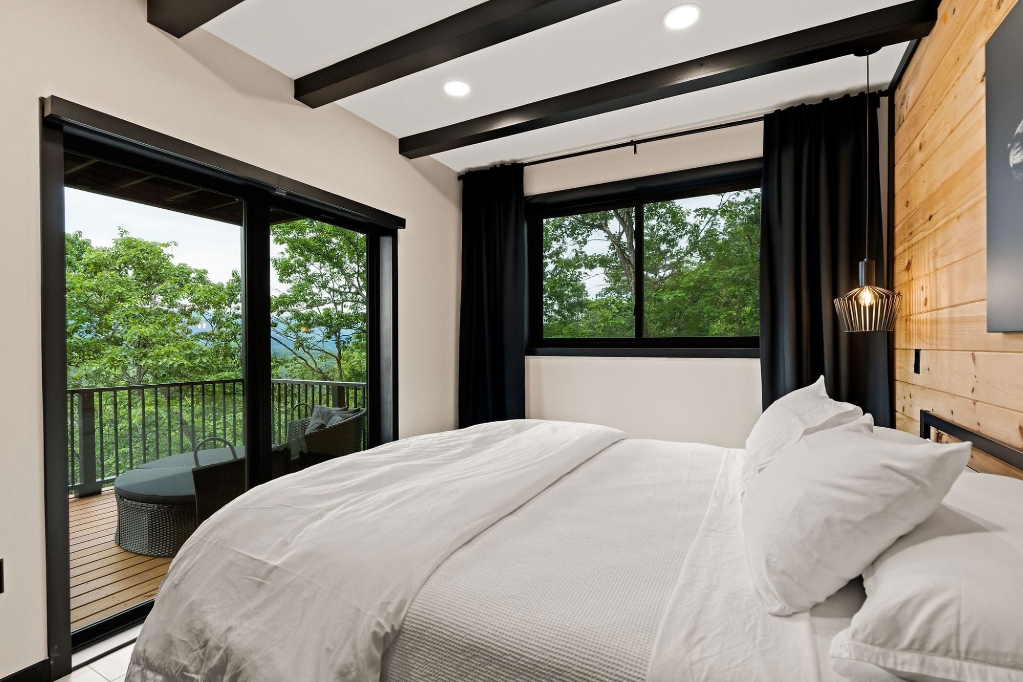 Bedroom opening through sliding glass doors to a private deck with a mountain view