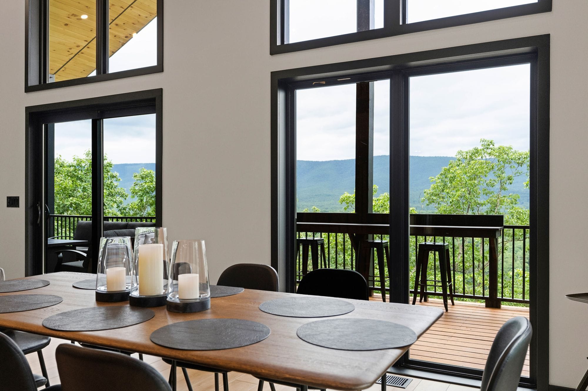 Dining table with candles and sliding doors opening to the deck and the view