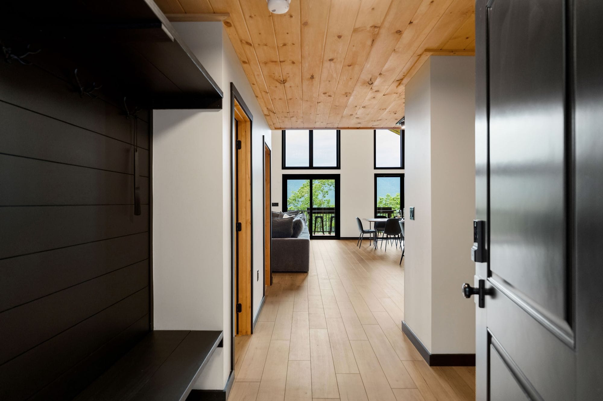 Hallway opening into the great room and dining, framed by the wall of windows and the mountains beyond