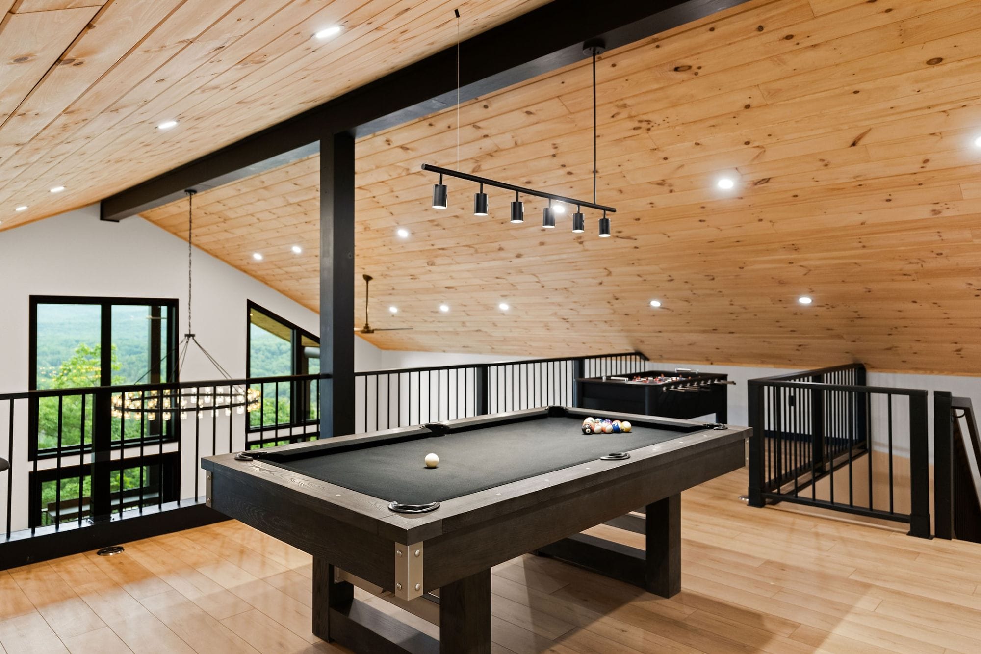 Loft game room with a pool table and foosball beneath the ring chandelier and mountain views