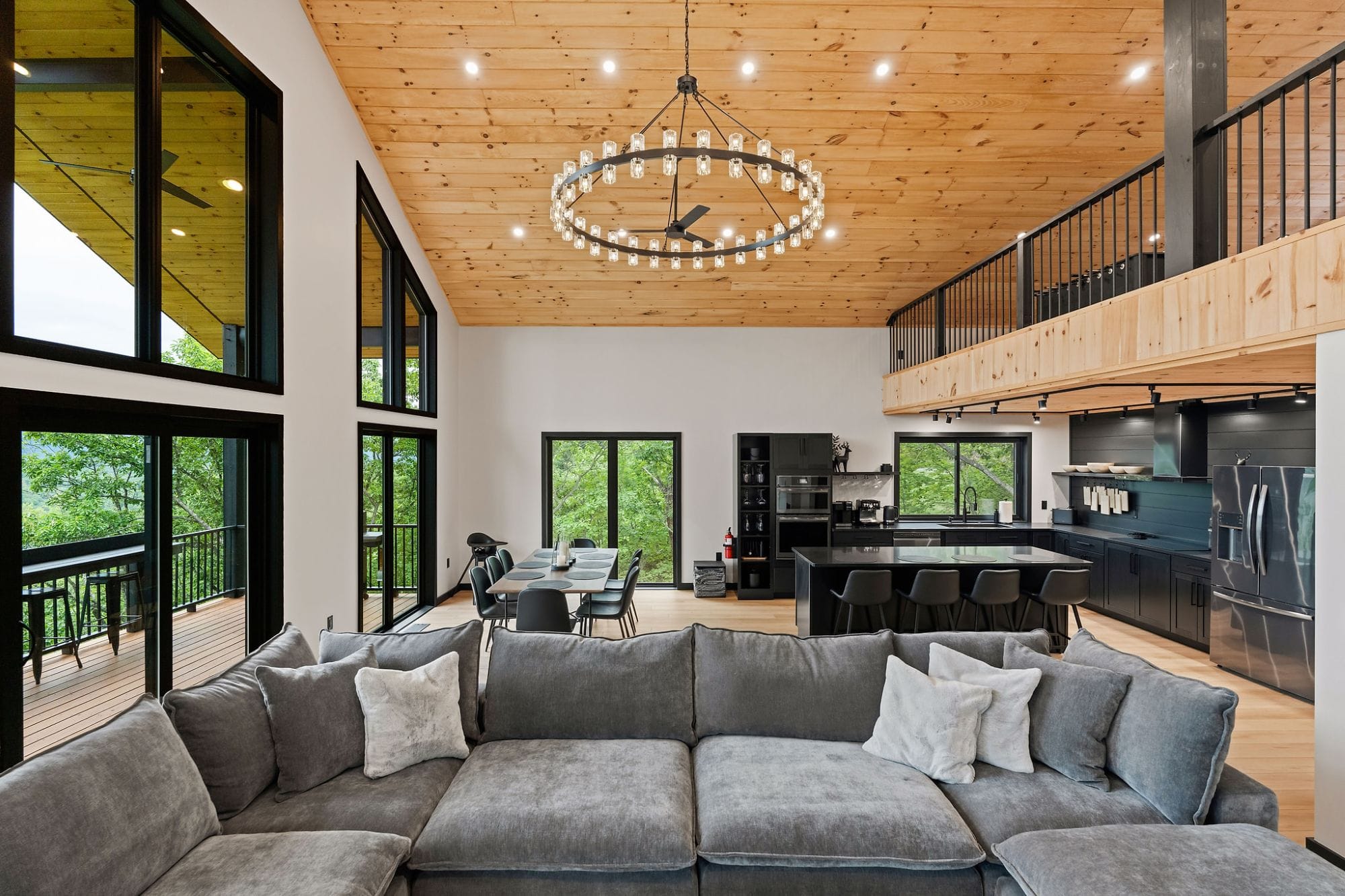 Open-plan great room, dining, and kitchen under the ring chandelier and loft