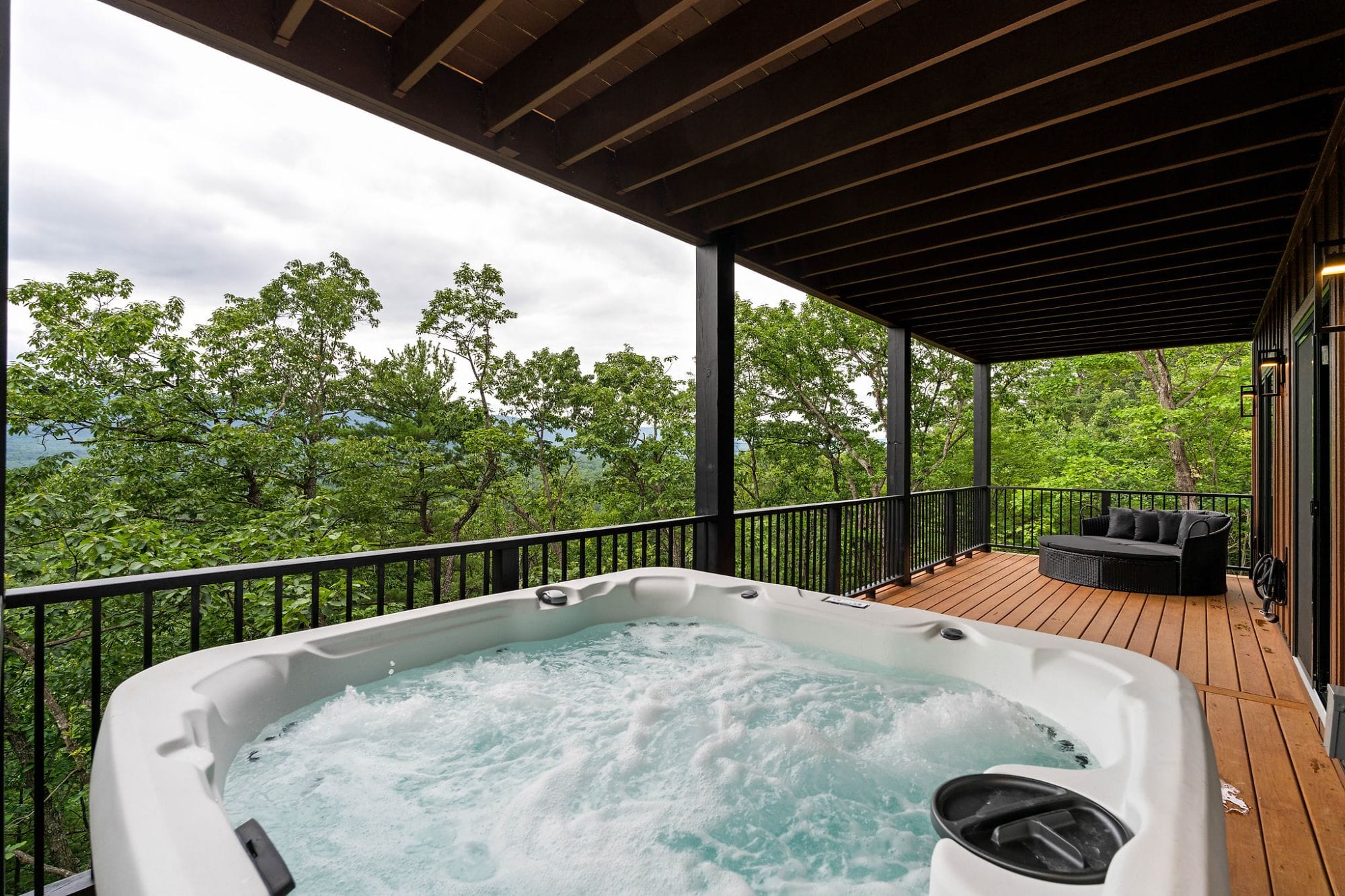Hot tub bubbling on the deck with a mountain view and a daybed alongside