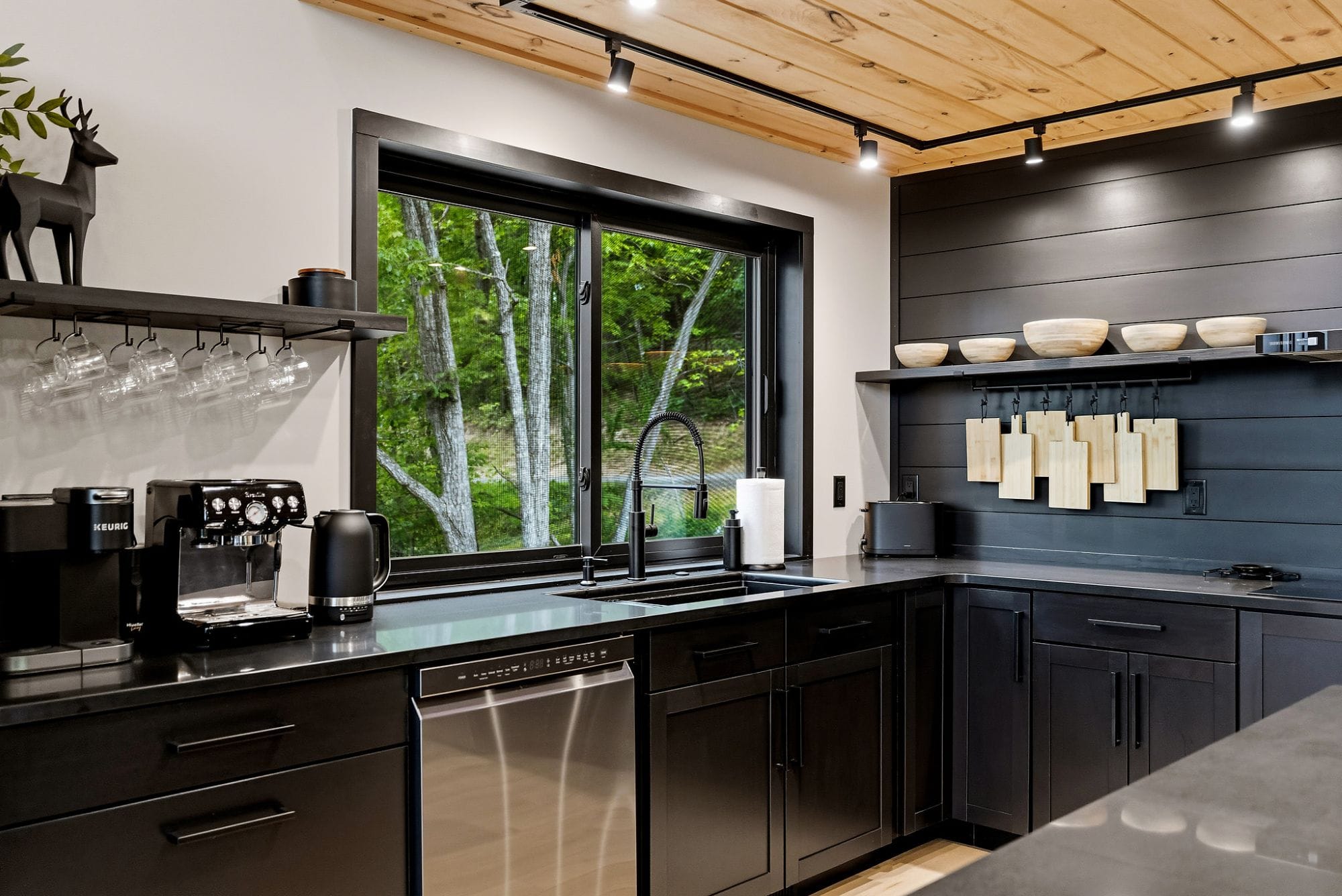 Coffee bar with a Breville espresso machine, Keurig, and kettle beneath hanging mugs
