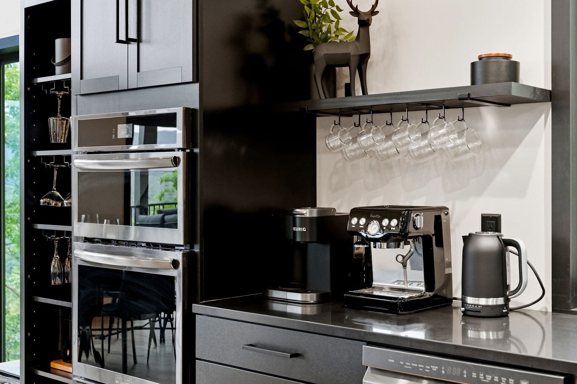 Coffee station and double wall ovens beside the glassware cabinet
