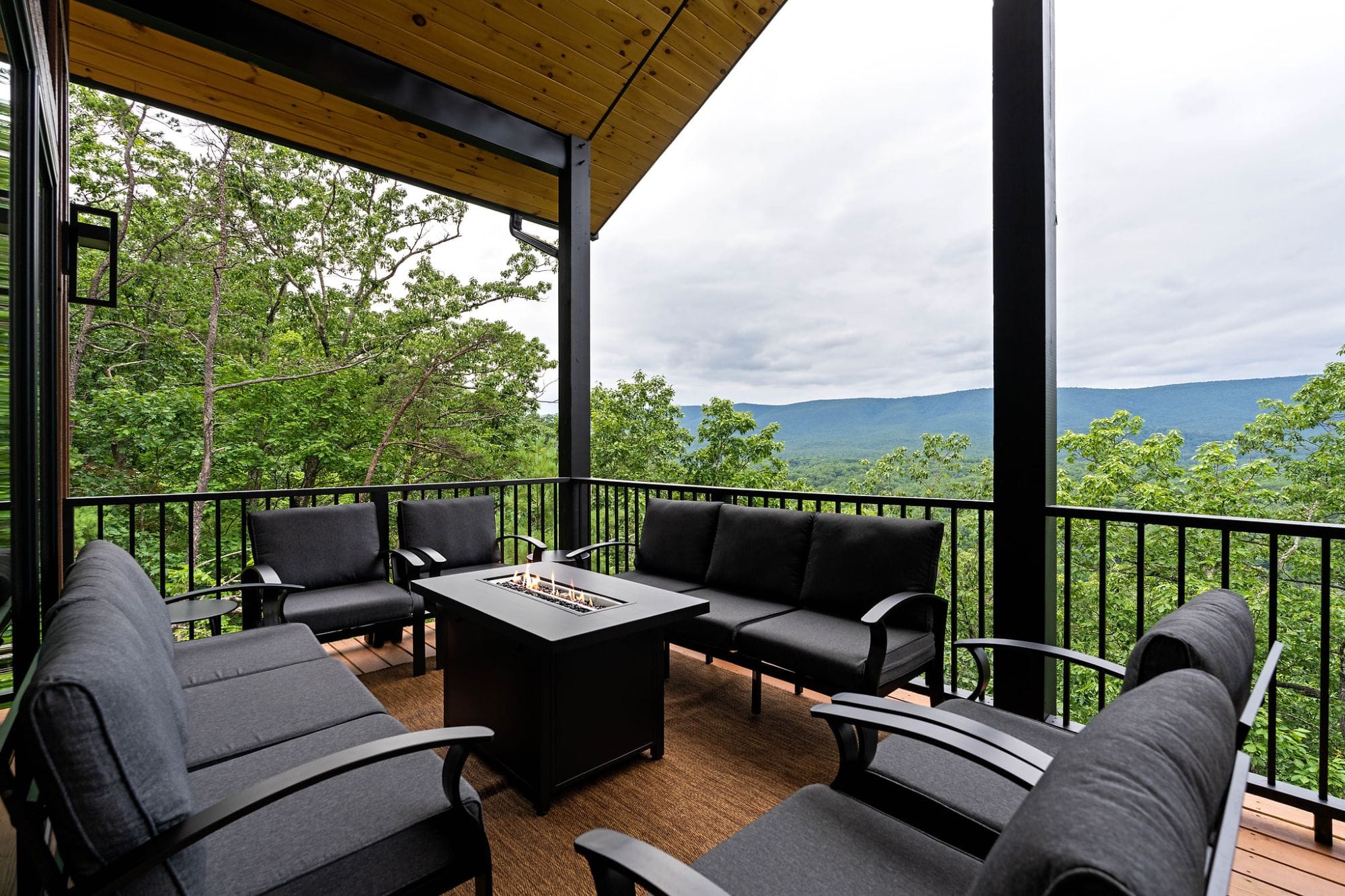 Covered deck with cushioned seating and a fire table overlooking the Shenandoah Valley